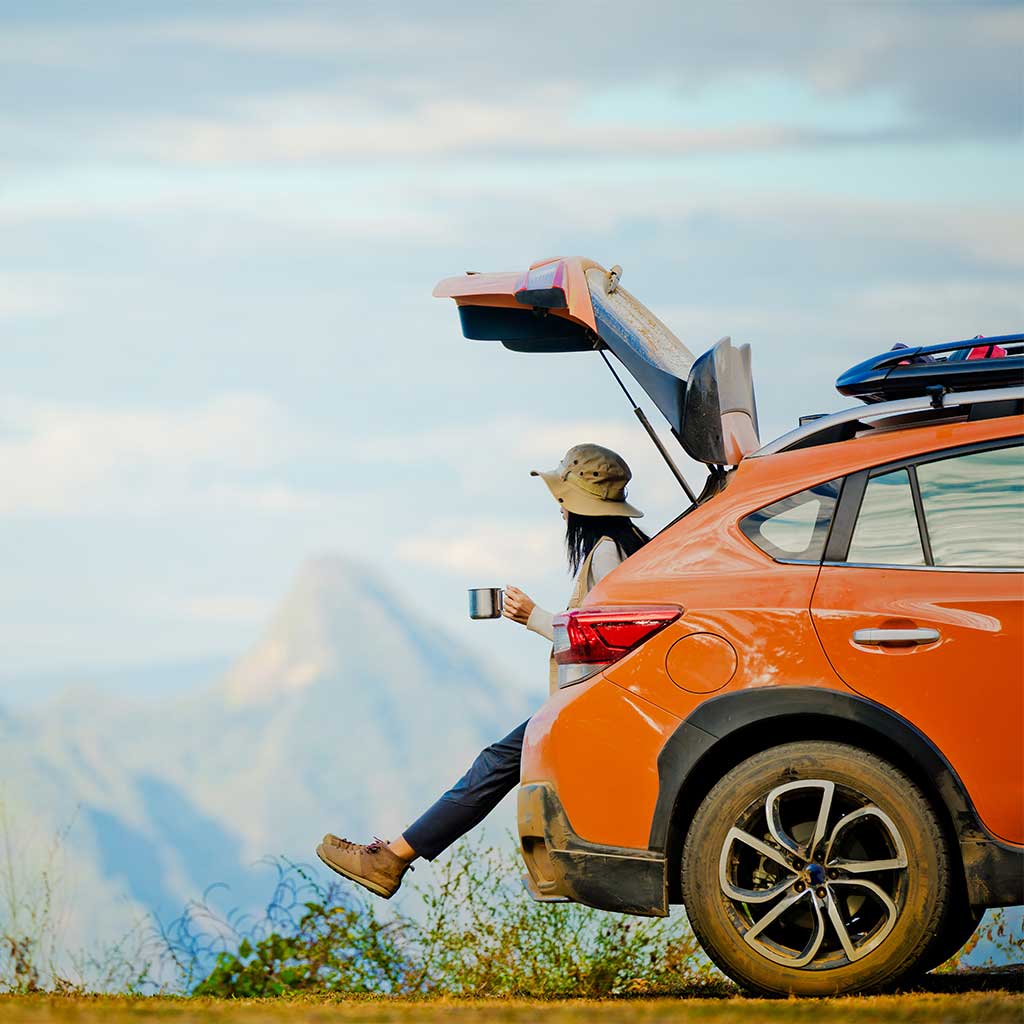 woman sitting in the back of her car looking at the mountains