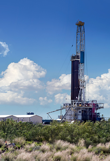 A jackrabbit runs in the foreground of the X16 Permian Basin oil rig.