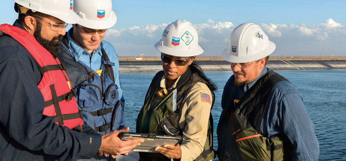 Team members look at a clipboard while looking over the water